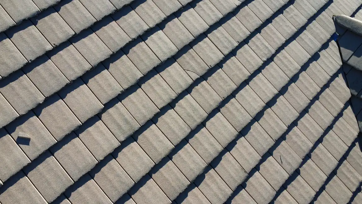 Gray concrete-looking roof tile with cracks and chipped edges