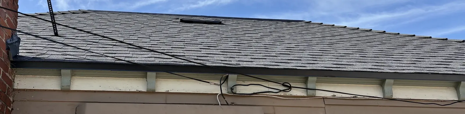Gray shingle roof with chimney and fascia detail